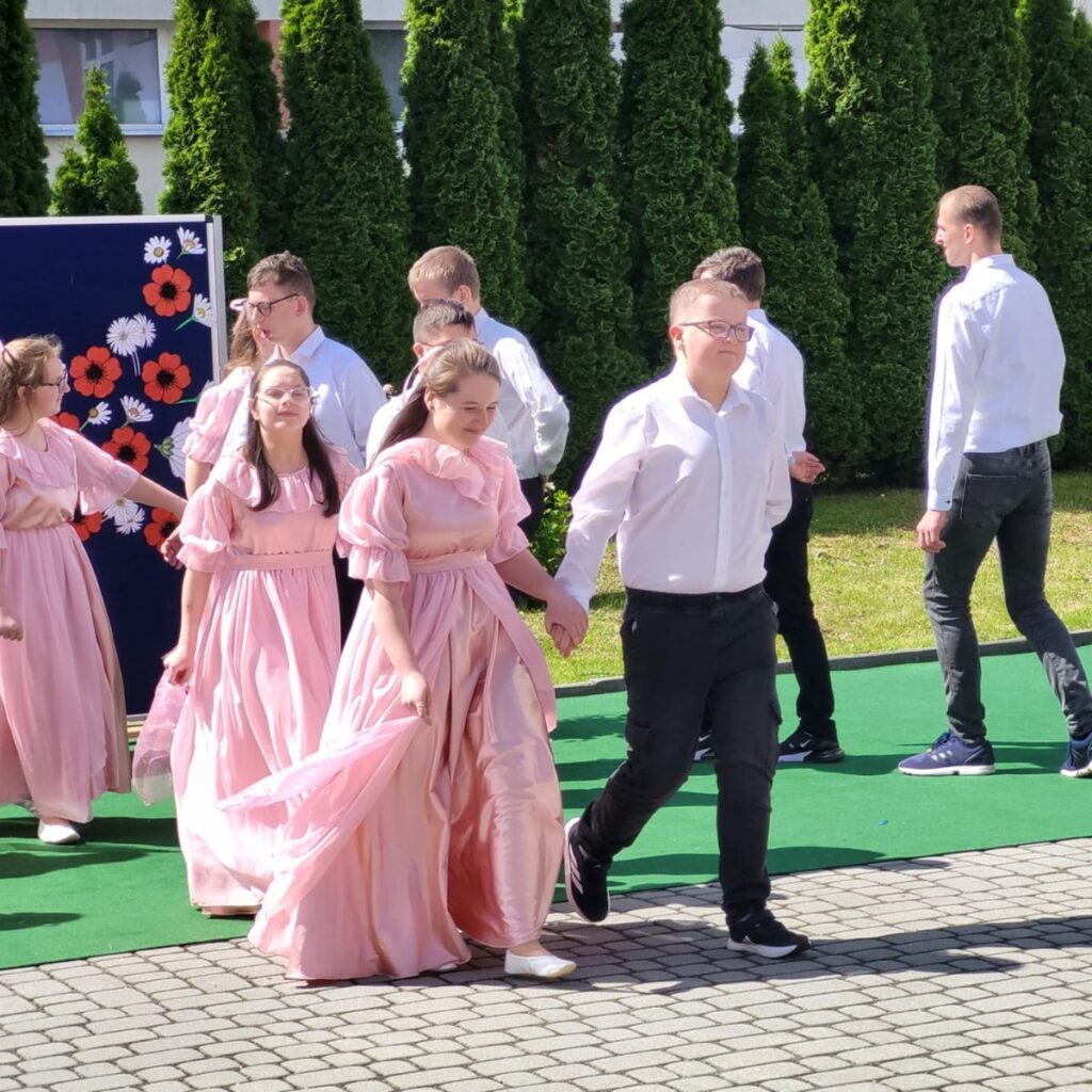 Uczestnicy projektu idą w parach podczas występu artystycznego na świeżym powietrzu