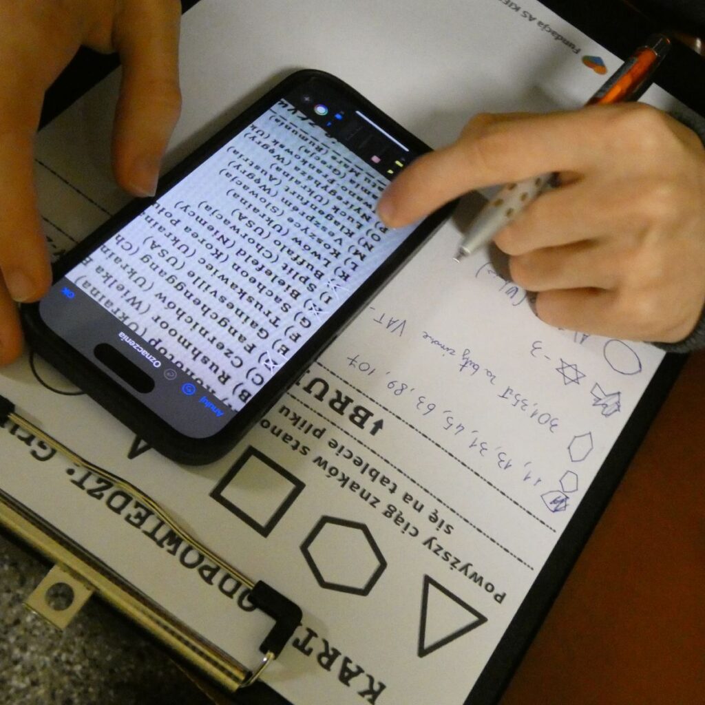 Uczestnik warsztatów korzysta ze smartfona do rozwiązania zadania logicznego