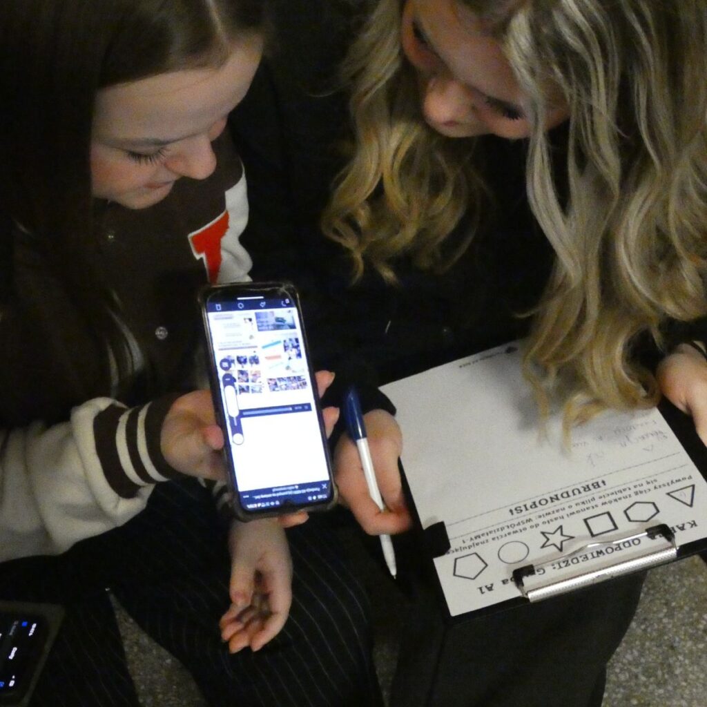 Dwie dziewczyny analizują informacje w telefonie podczas zajęć o kompetencjach cyfrowych