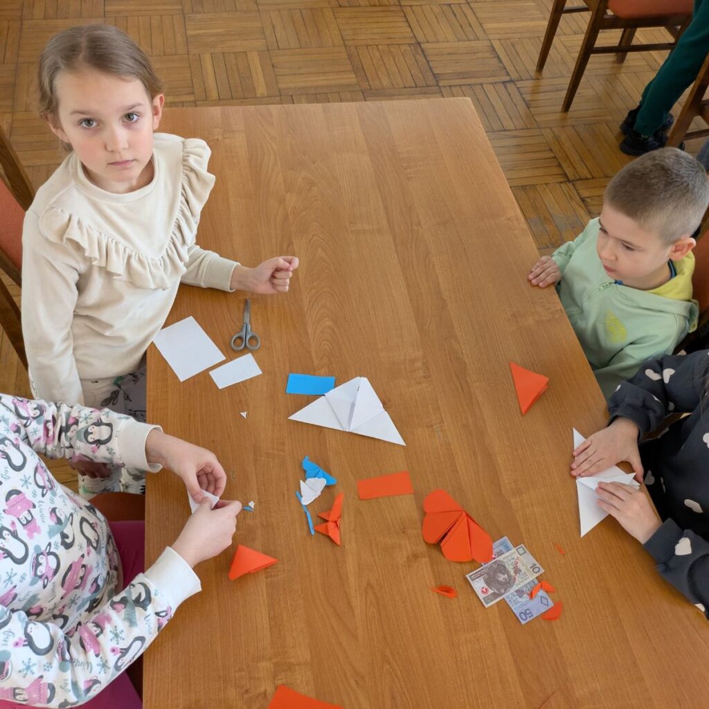 Dzieci wykonują papierowe zadania edukacyjne podczas zajęć o ekonomii