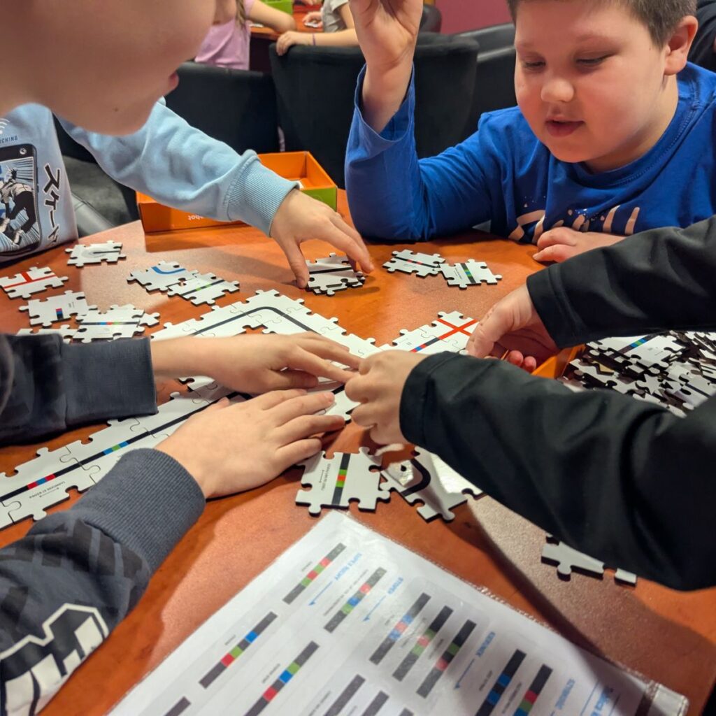Dzieci układają elementy planszy do programowania z robotem Ozobot