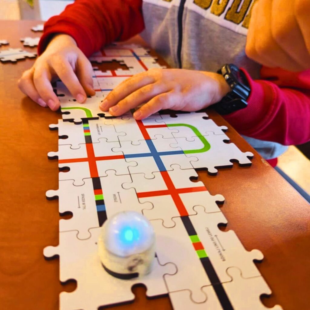 Dziecko steruje robotem Ozobot na planszy z kolorowymi trasami