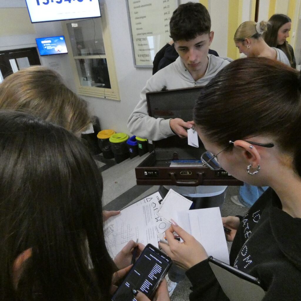 Młodzież analizuje materiały i wskazówki podczas gry edukacyjnej w grupie