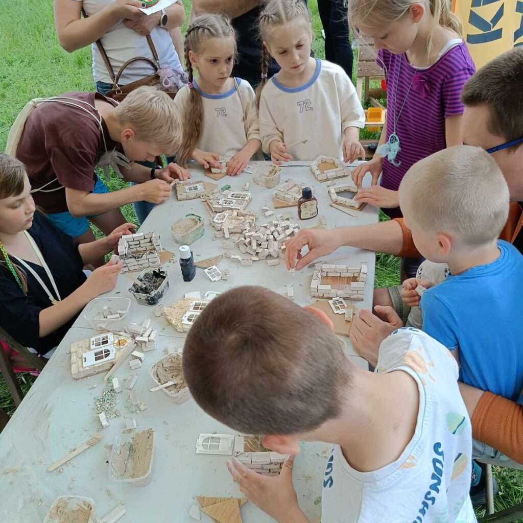 Dzieci przy stole tworzą modele budynków z małych cegieł podczas warsztatów