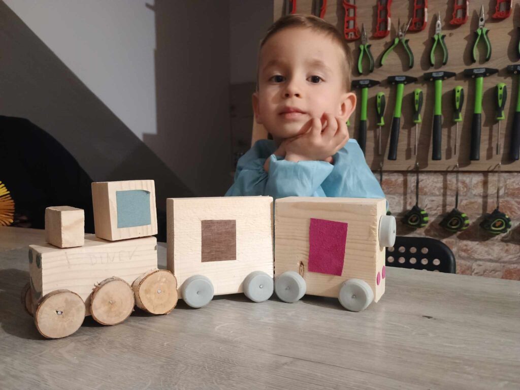 Uczestnik zajęć Majster Klub z własnoręcznie wykonanym projektem z drewna