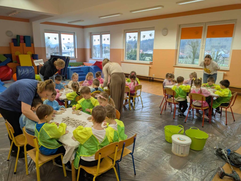 Dzieci podczas warsztatów Majster Klub pracują przy stolikach z opiekunami