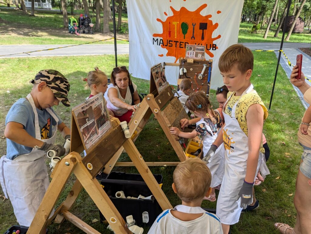 Uczestnicy wydarzenia Majster Klub pracują przy interaktywnym stanowisku warsztatowym